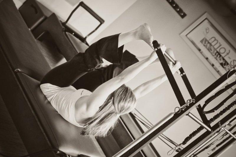 Person exercising on Pilates reformer machine.